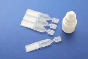 A group of different types of artificial tears laying on a blue surface
